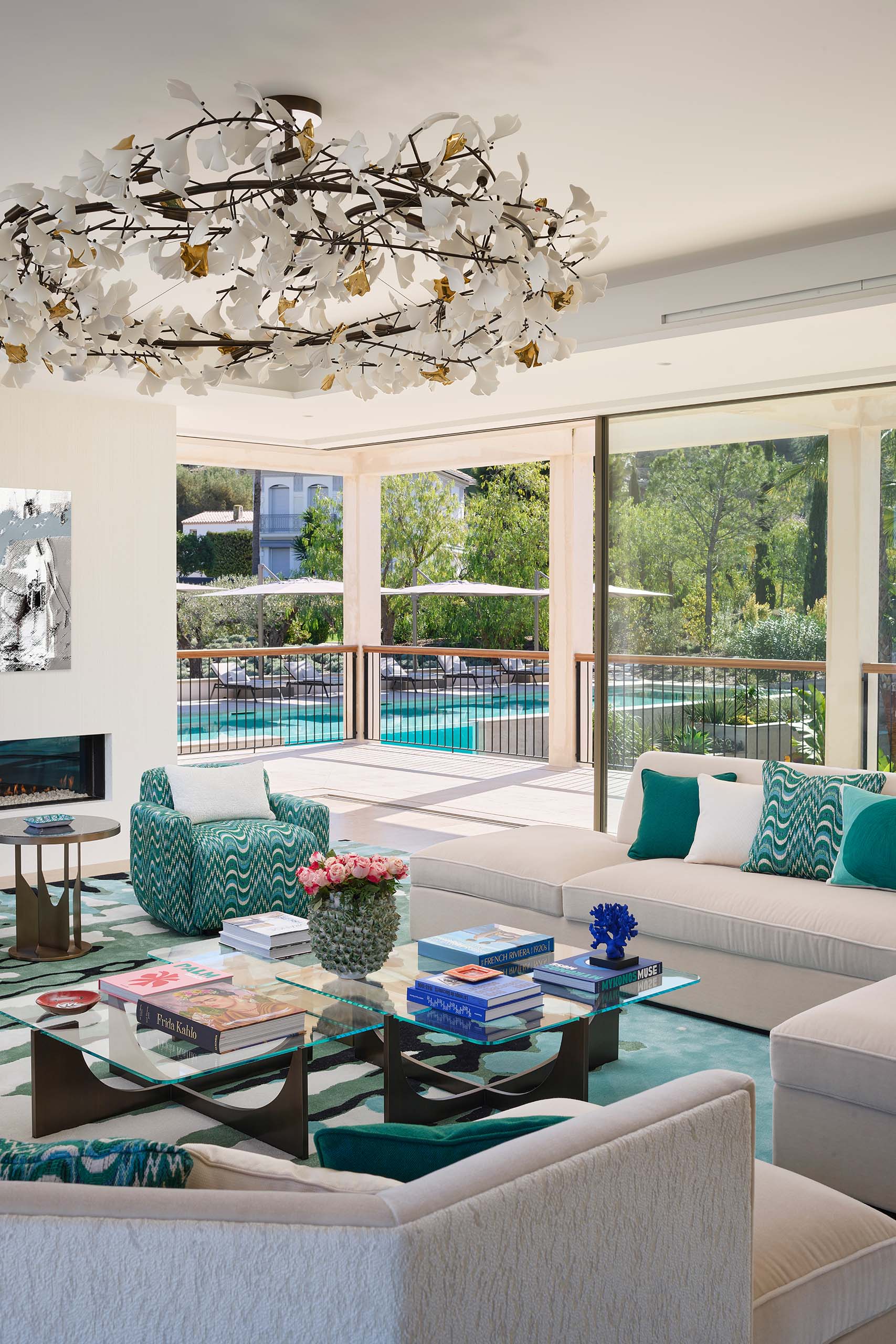 Bright reception room at Domaine de la Belle Étoile with teal soft furnishings, floral chandelier and pool terrace views