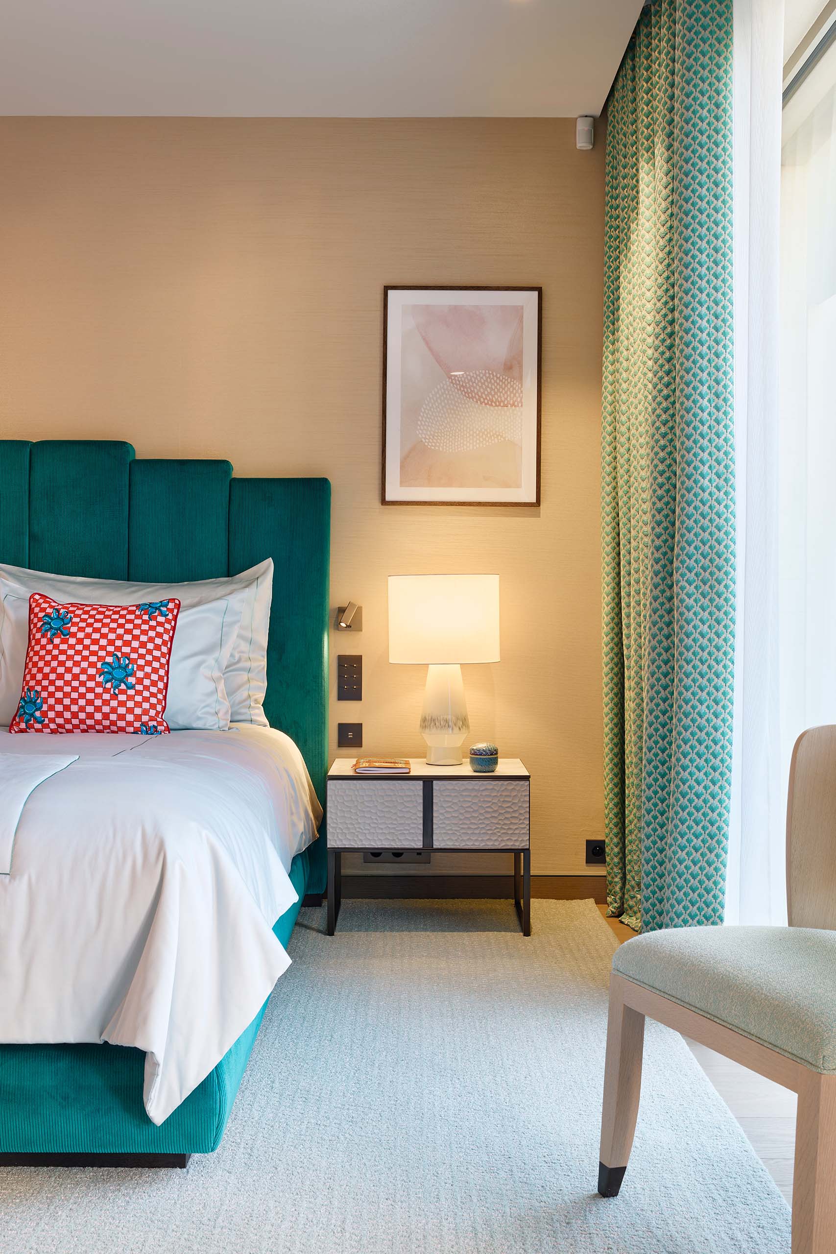 Bedroom detail at Domaine de la Belle Étoile with teal velvet headboard and green patterned floor-to-ceiling curtains