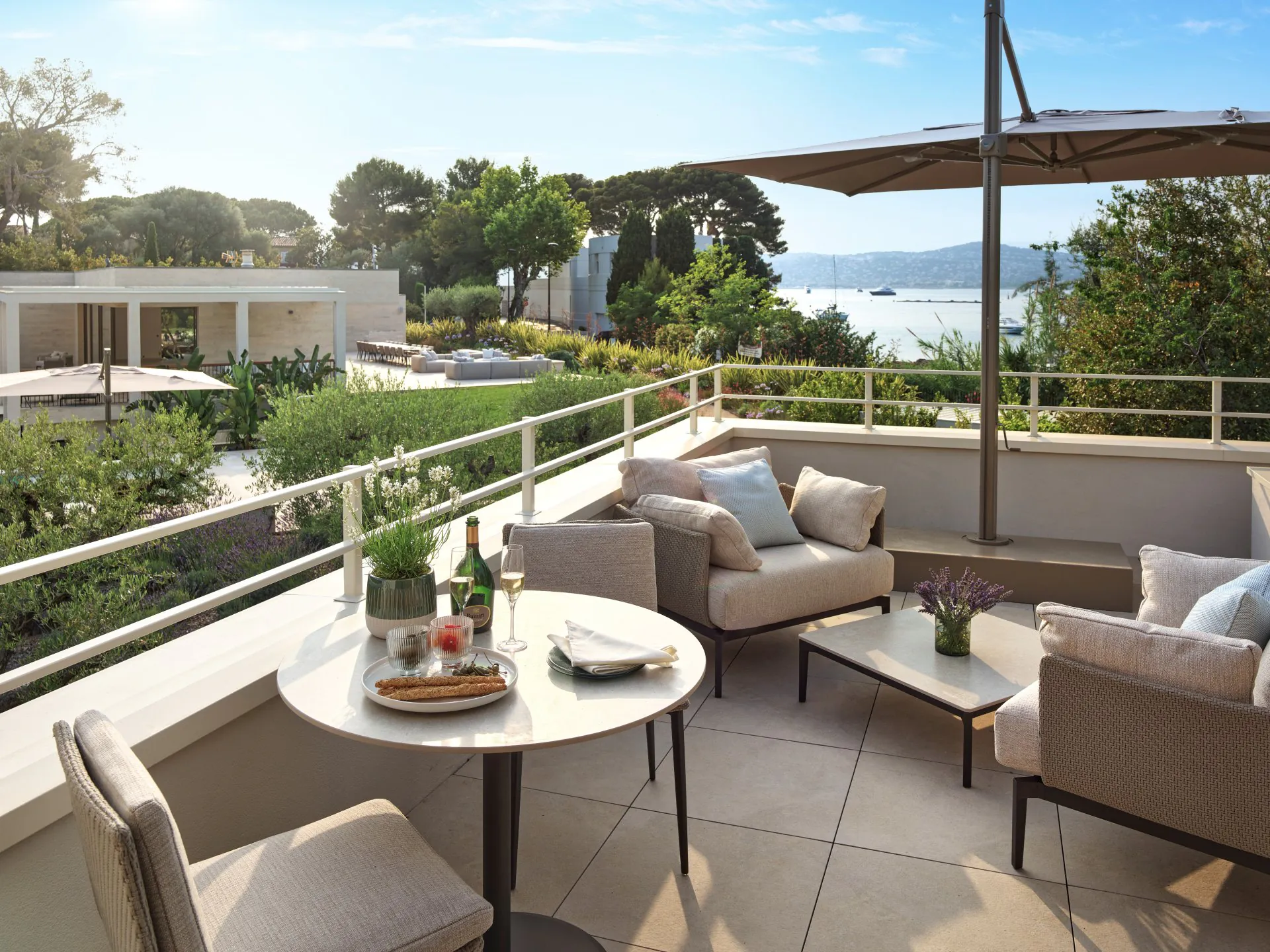 Private terrace at Domaine de la Belle Étoile with outdoor dining, lounge seating, champagne and sea views over the gardens