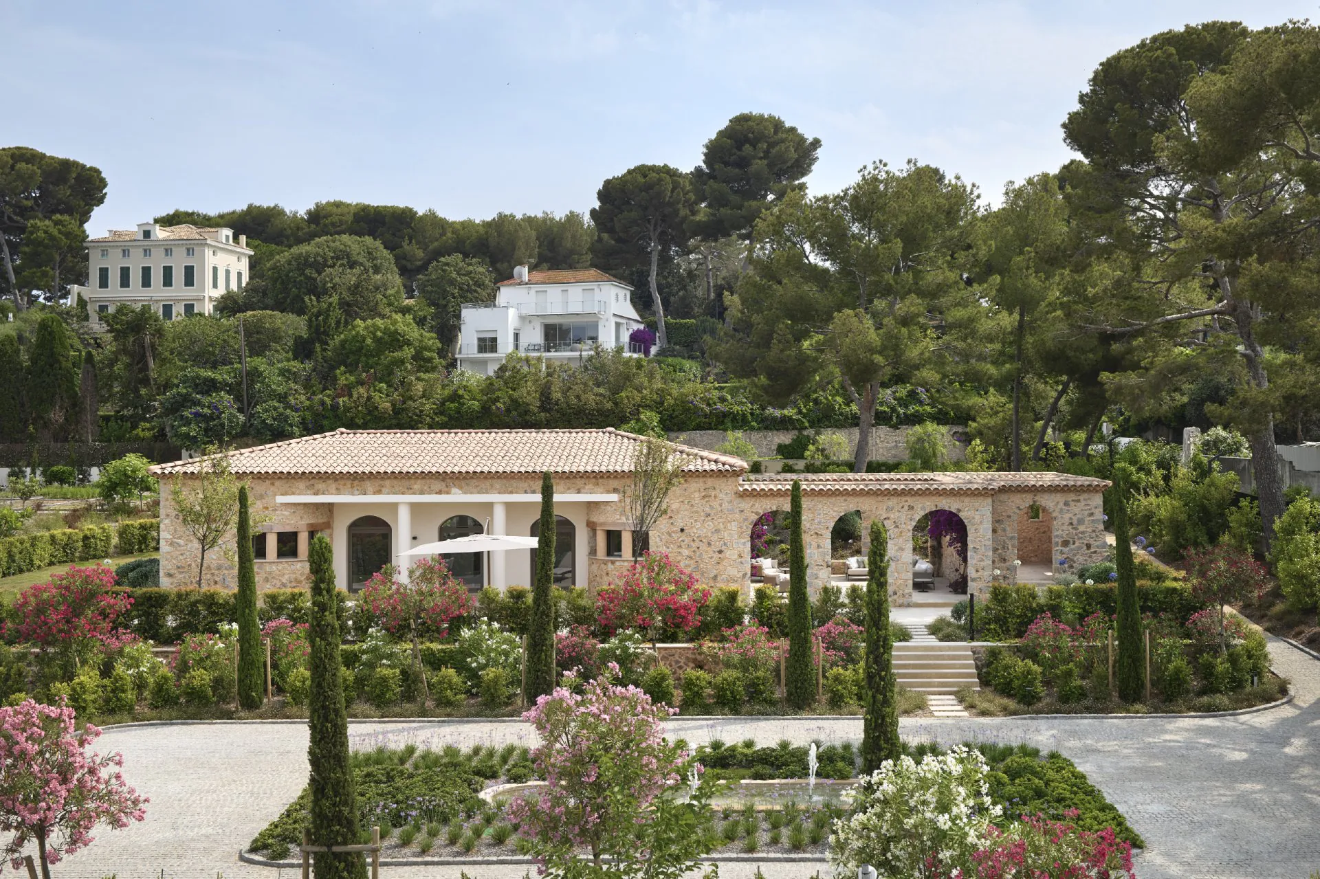 Domaine de la Belle Étoile stone villa exterior with terracotta roof, cypress trees, and flowering Mediterranean gardens
