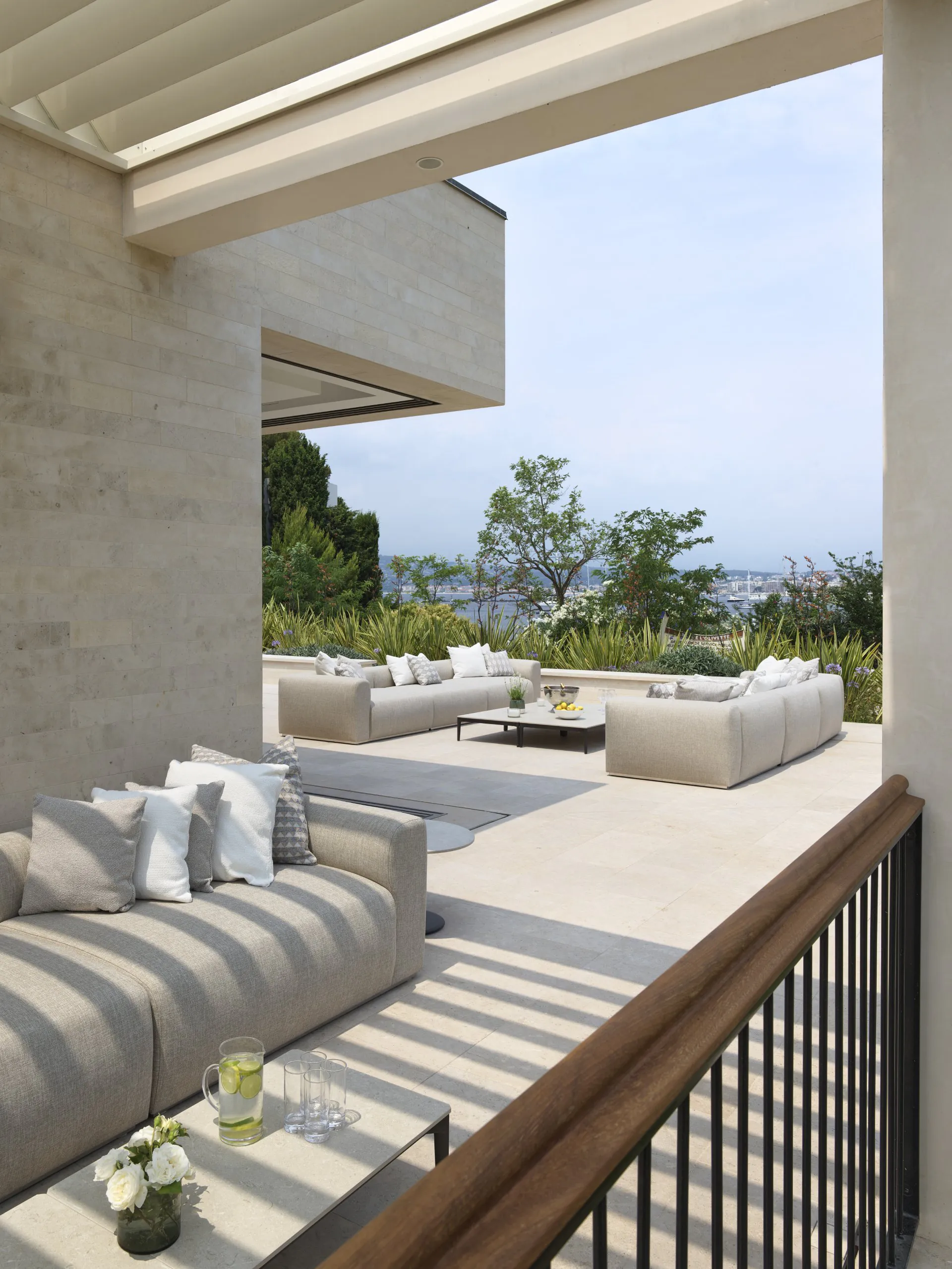 Covered outdoor terrace at Domaine de la Belle Étoile with neutral lounge seating, stone flooring and panoramic sea views