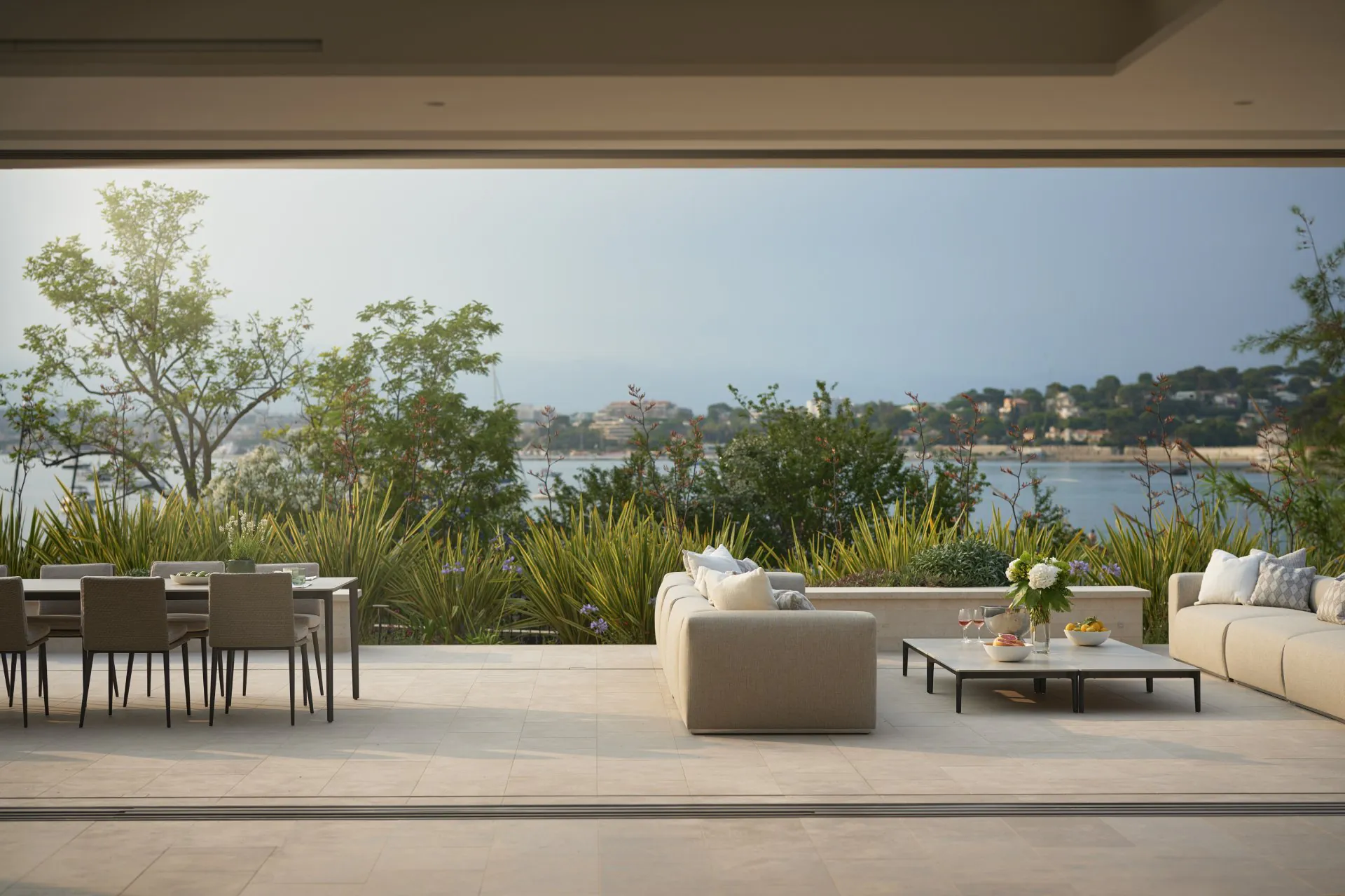 Waterfront terrace at Domaine de la Belle Étoile with outdoor dining, lounge seating and uninterrupted views over the bay