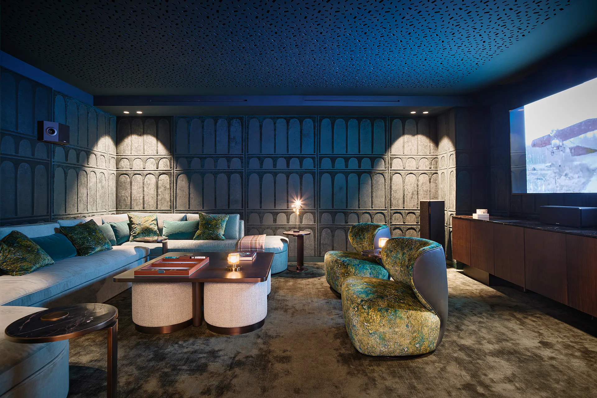 Private cinema room at Domaine de la Belle Étoile with textured blue walls, velvet seating and large projection screen