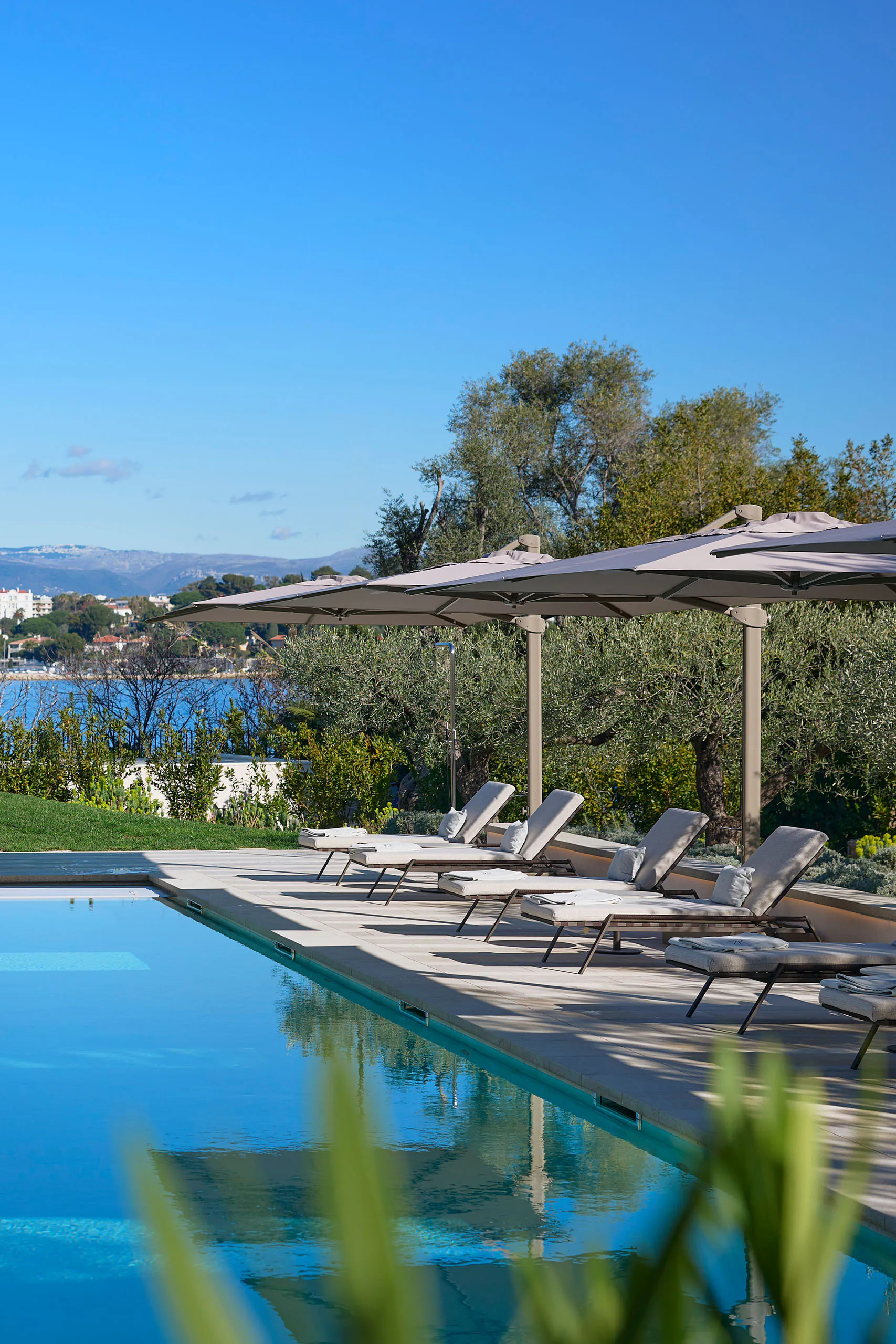 Outdoor pool terrace at Domaine de la Belle Étoile with sun loungers, parasols and panoramic sea views